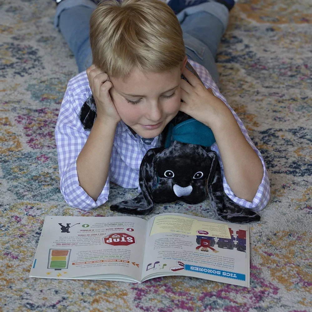 A child reading with a manimo weighted dog resting across their lap.