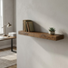 A realistic photo of the Entrepot La Grange inc 48-inch Medium Walnut floating shelf mounted in a home office above a desk, featuring books and a plant. (About 130 characters)