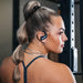 Side profile of a woman wearing Wicked Audio Raen sport earbuds at the gym