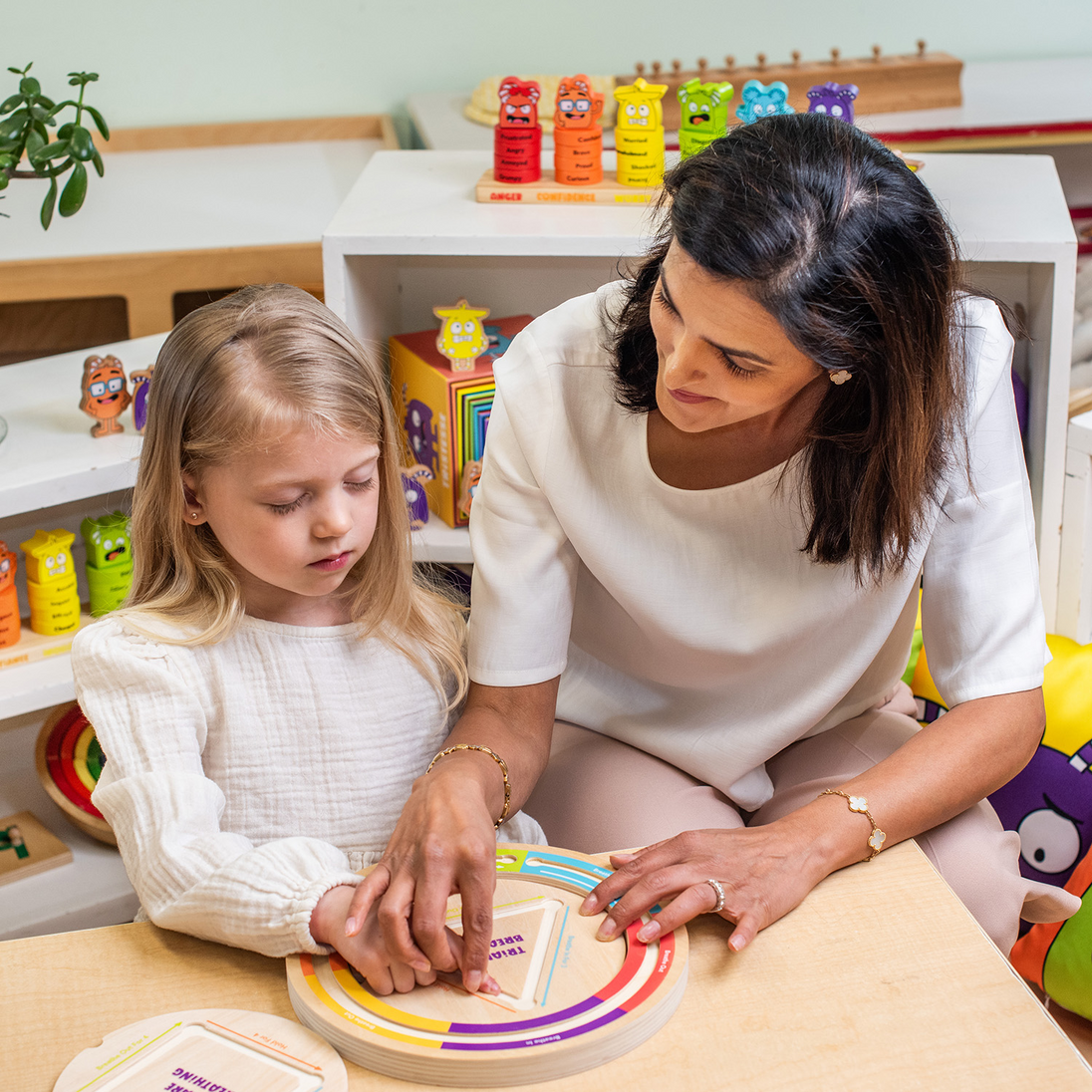 Adult and young girl tracing the rainbow arch Calming Breathing Board together at a table