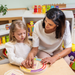 Adult and young girl tracing the rainbow arch Calming Breathing Board together at a table