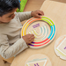 Child tracing the grooves of a round wooden breathing board with a finger