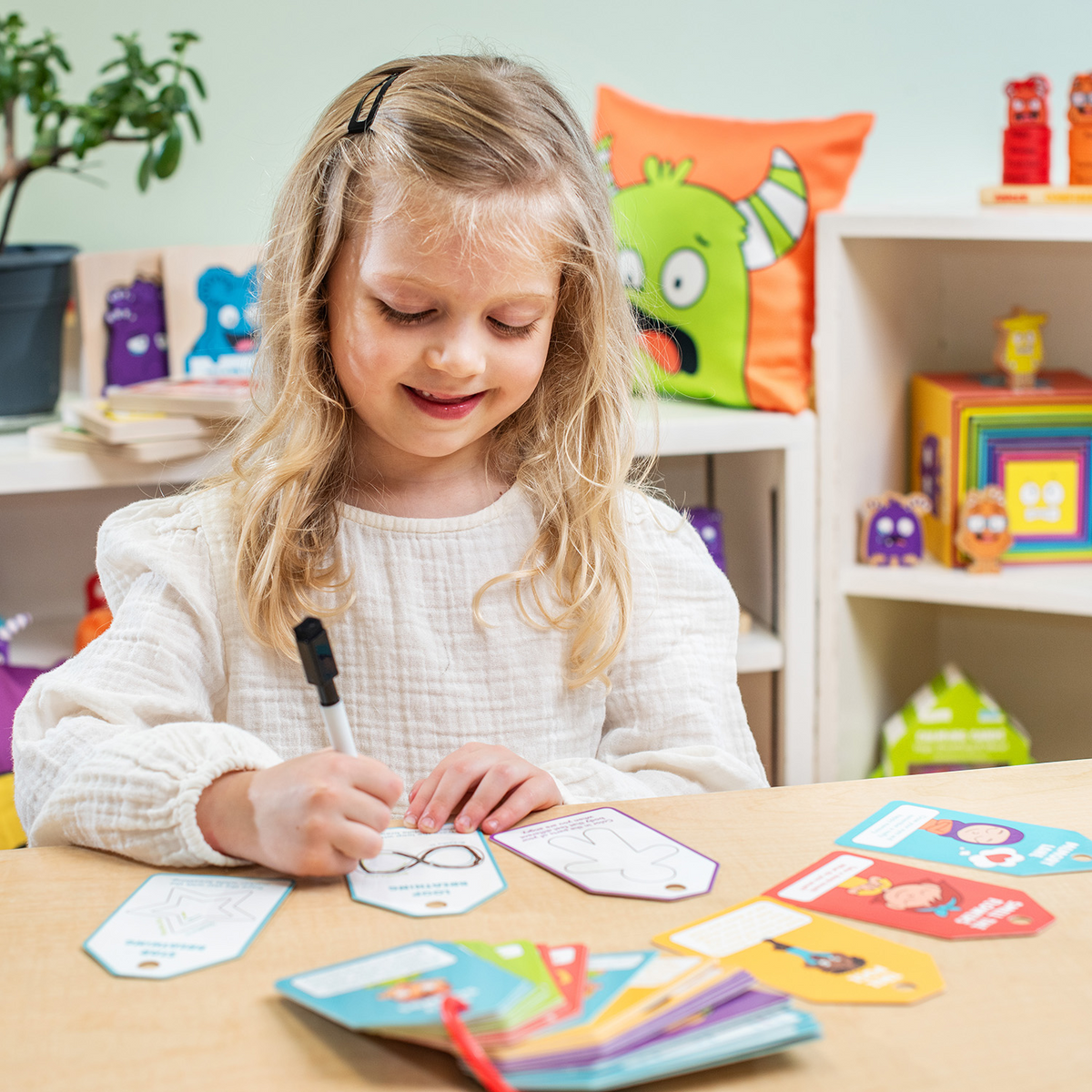 Young girl drawing on a Calming Cards dry-erase card at a table