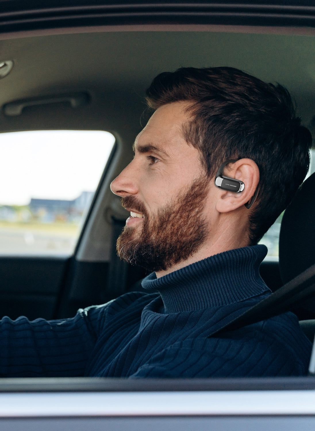 Man driving while wearing OPN Sound Aria Pro open-ear headphones