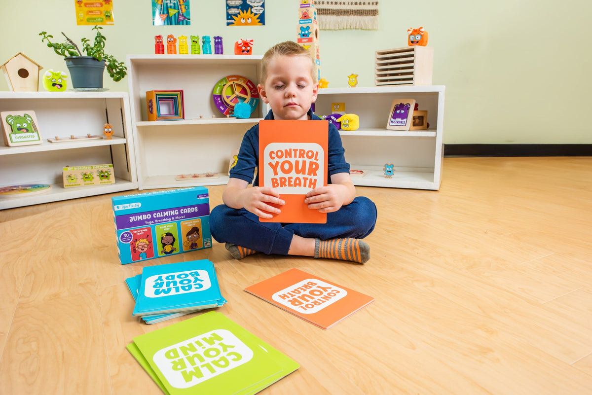 Child seated on a classroom floor with the Jumbo Calming Cards