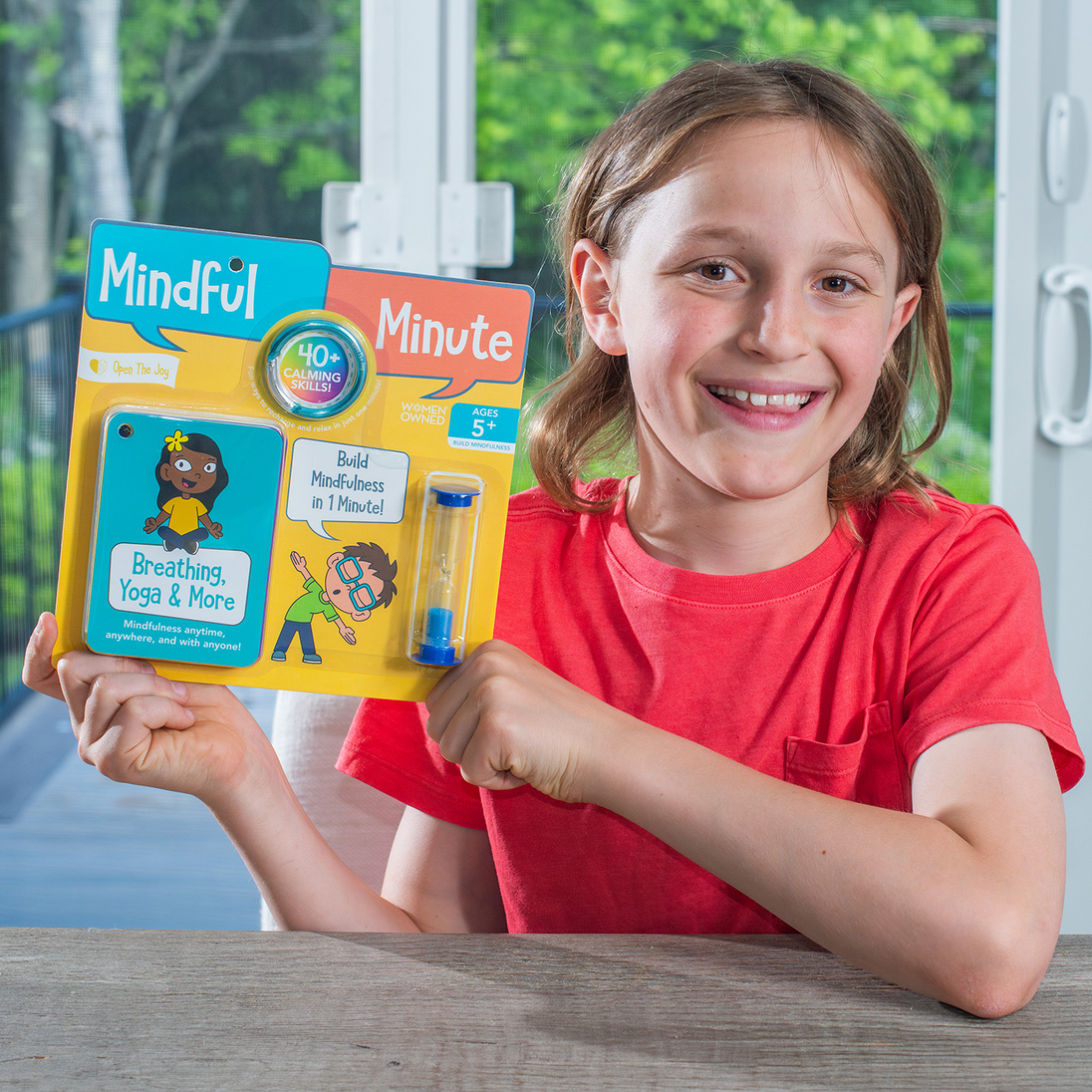 Girl holding up the Mindful Minute card pack outdoors
