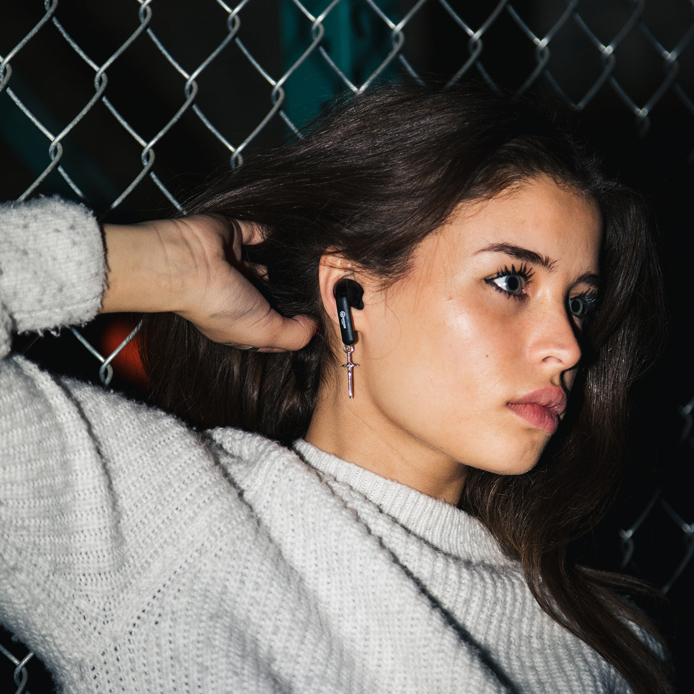 Woman wearing a Wicked Audio Mojo 500 earbud outdoors at night