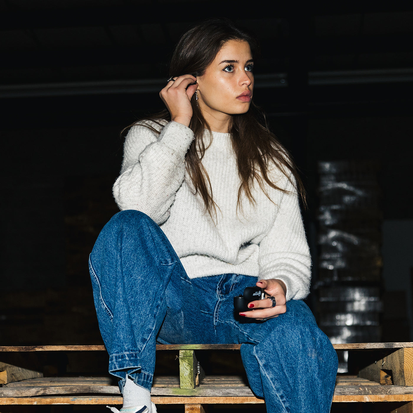 Woman wearing Wicked Audio Mojo 800 earbuds, seated outdoors at night