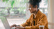Woman working at a laptop wearing OPN Sound Swym+ headphones with noise-cancelling mics