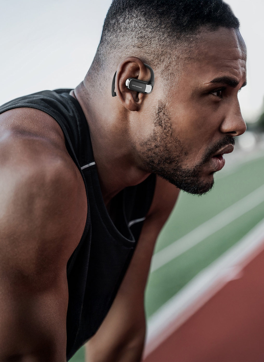 Athlete on a running track wearing OPN Sound Aria Pro open-ear headphones