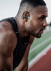 Athlete on a running track wearing OPN Sound Aria Pro open-ear headphones