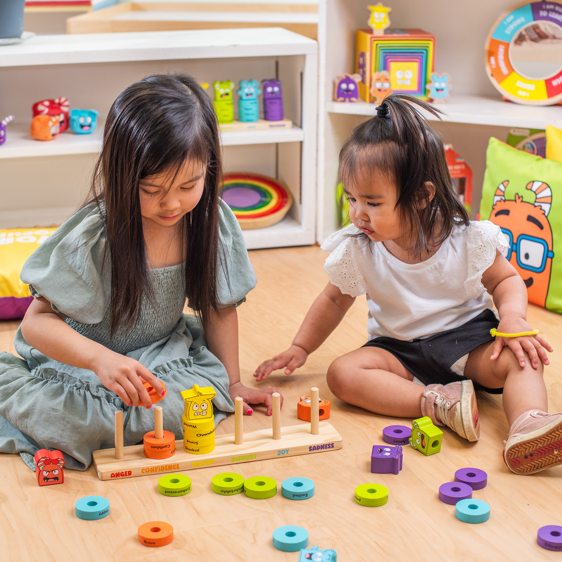 Two girls playing with the Emotions Stacking Rings on the floor