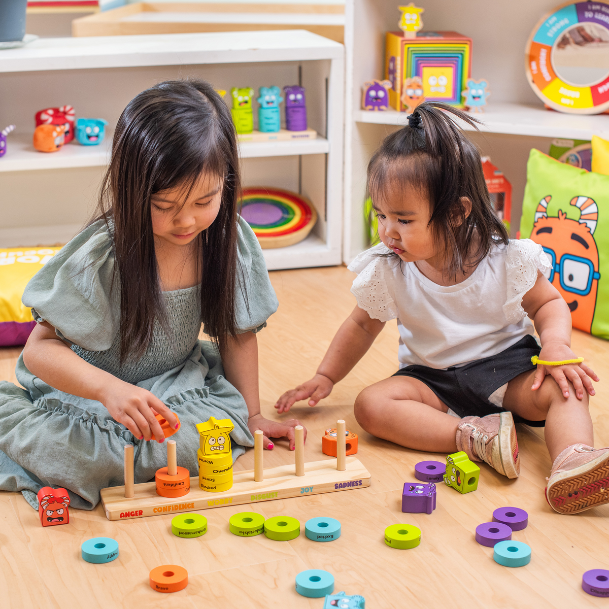 Two girls playing with the Emotions Stacking Rings on the floor
