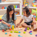 Two girls playing with the Emotions Stacking Rings on the floor