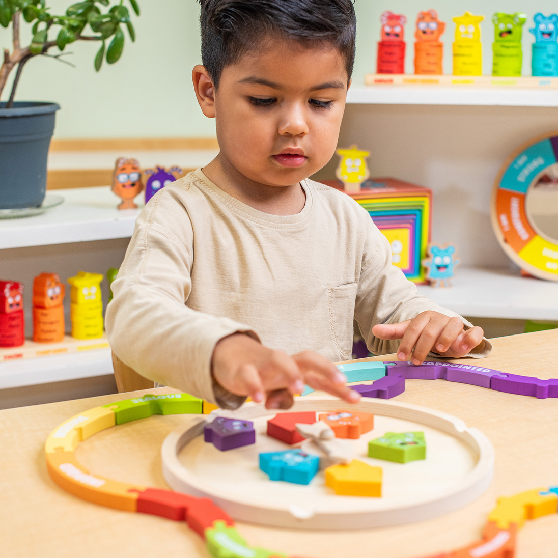 Toddler playing with the My Emotions Wheel puzzle at a table